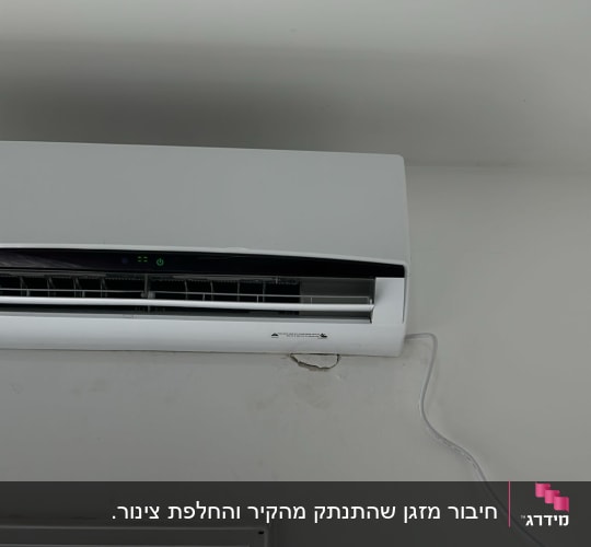 מזגן מותקן על קיר עם כבל חשמל